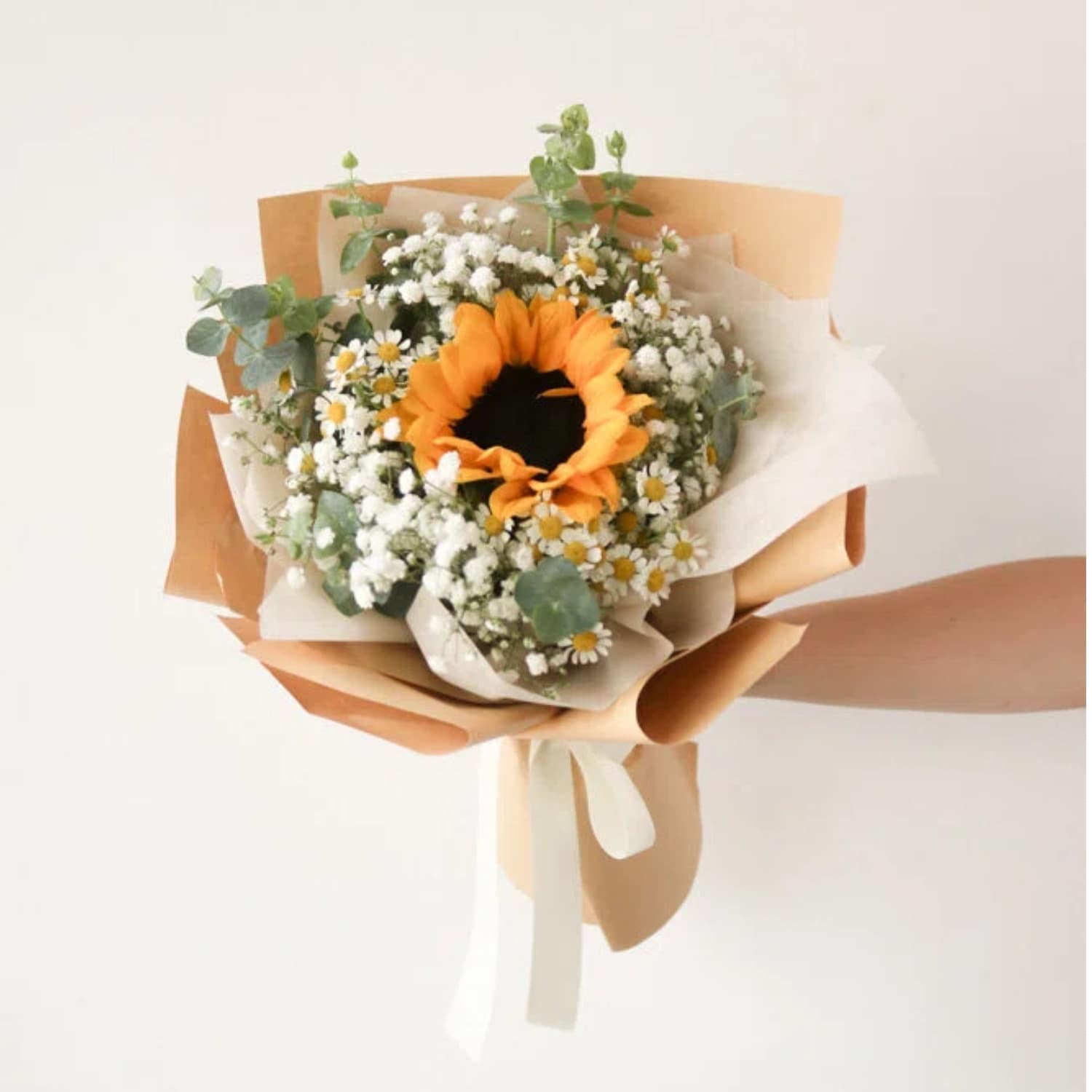 Orange sunflower, white daisies, white baby's breath in a brown wrap, tied with cream ribbon. Orange sunflower, white daisies, white baby's breath in a brown wrap, tied with cream ribbon.